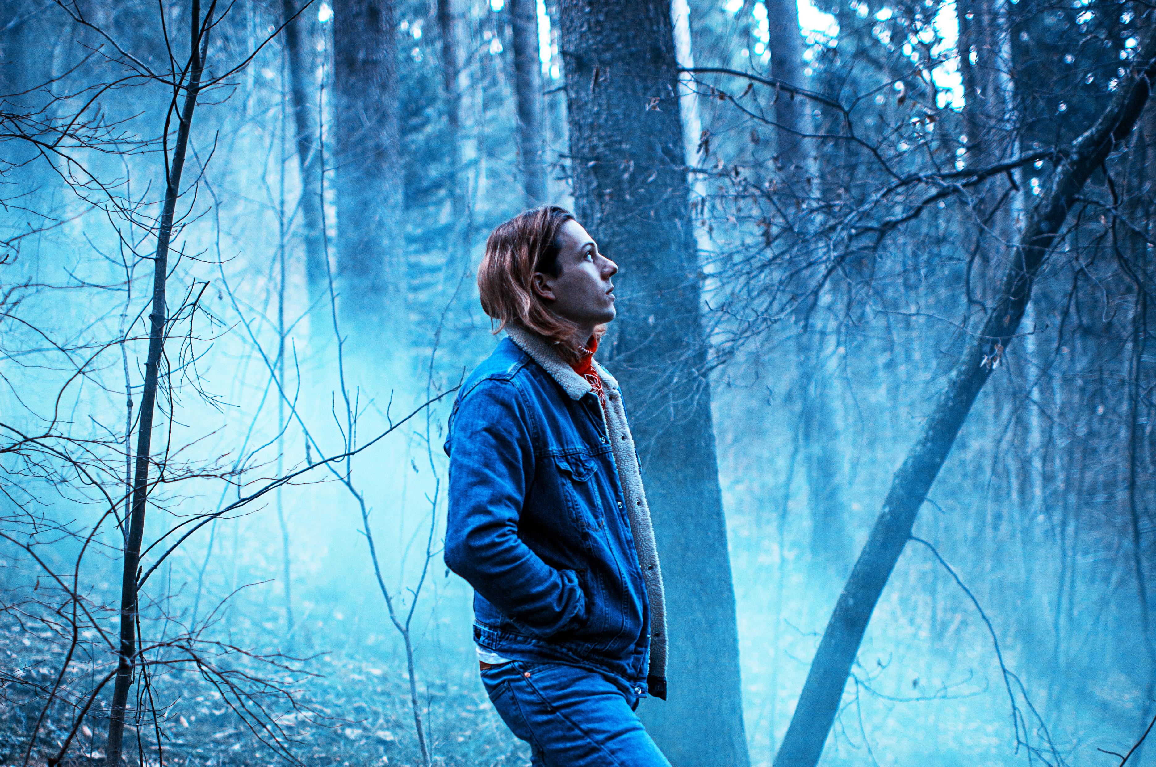 Alex Price looking ominously up at the sky in dark woods Alex Price looking ominously up at the sky in dark woods