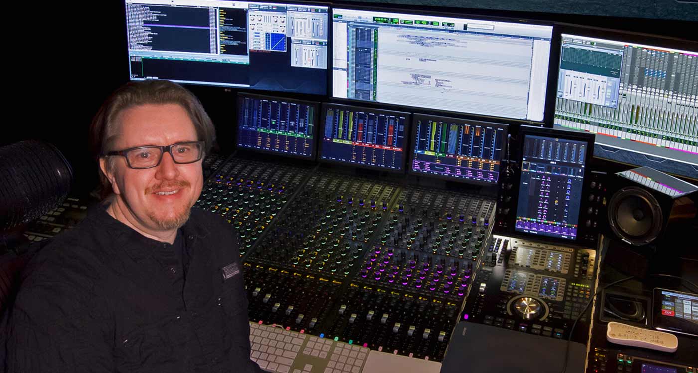 Charles Deenen sat in front of film mixing console in post production studio Charles Deenen sat in front of film mixing console in post production studio