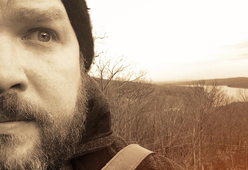 Closeup of David Baron outdoors on a hill by a lake Closeup of David Baron outdoors on a hill by a lake