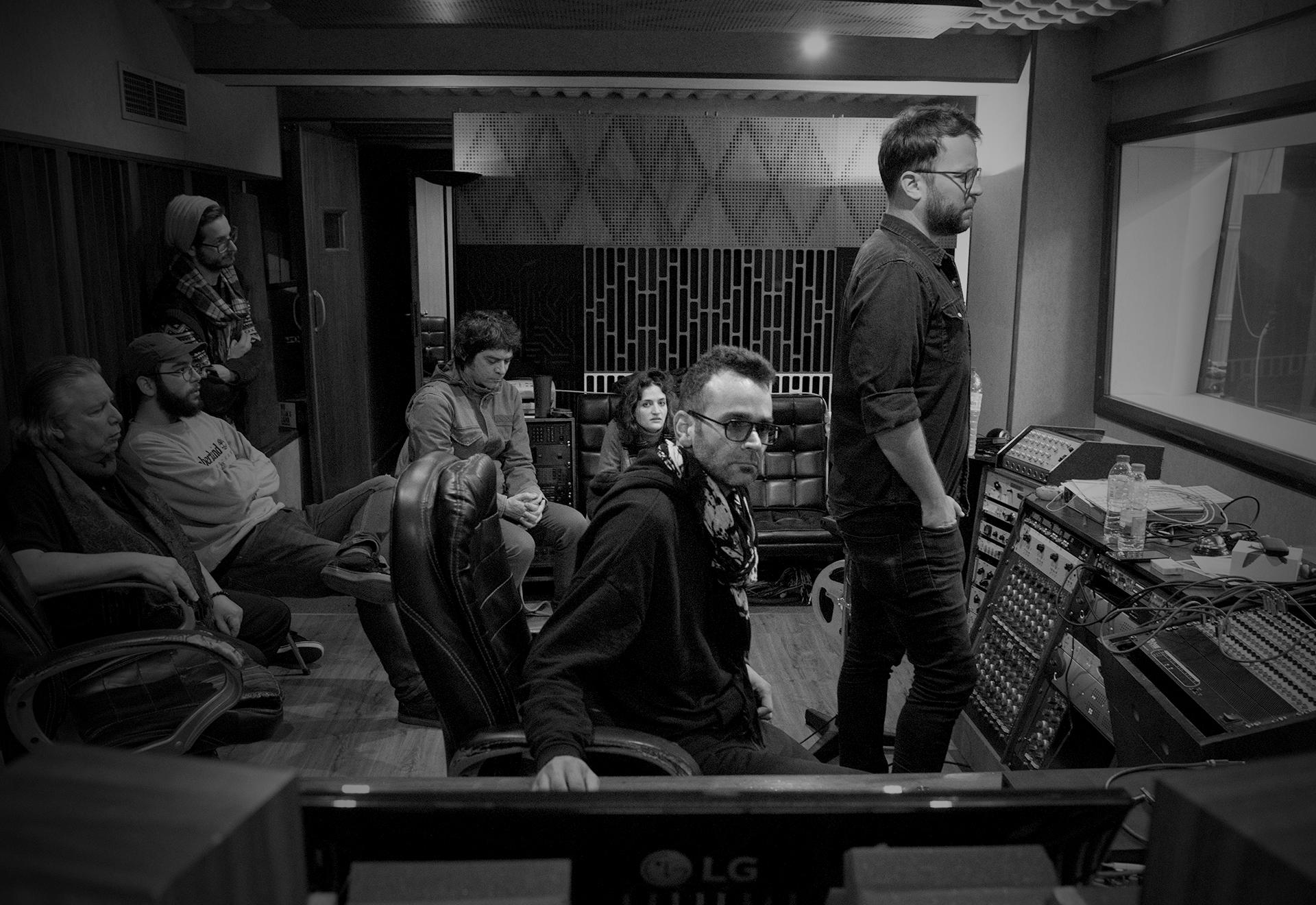 Hector Castillo sat in studio with several students looking through the window at the recording artist in the recording room Hector Castillo sat in studio with several students looking through the window at the recording artist in the recording room