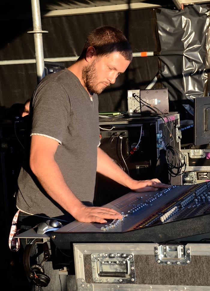 Richard Nicholson operating a live sound desk at a festival outdoors Richard Nicholson operating a live sound desk at a festival outdoors