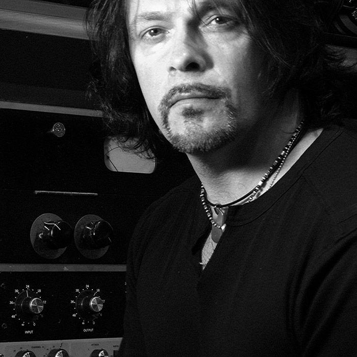 Richard Chycki stodd in front of analogue hardware in black and white Richard Chycki stodd in front of analogue hardware in black and white